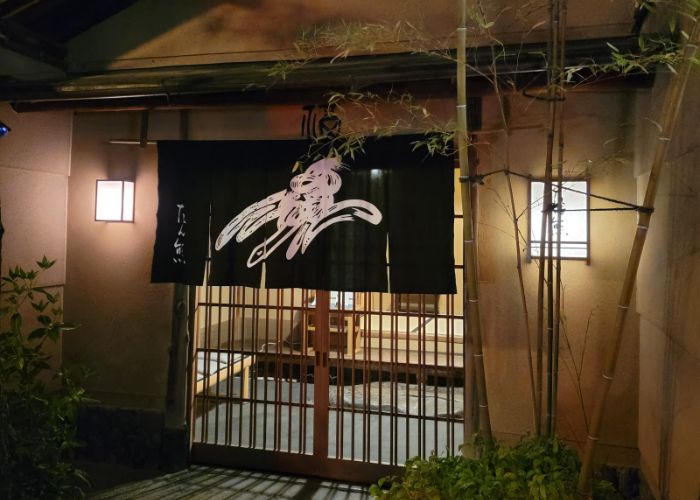 The front entrance to Honke Tankuma Honten, decorated with bamboo and a traditional sliding door.